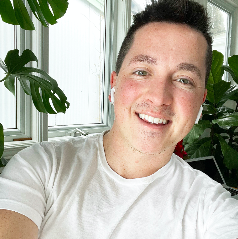 Brent smiling with plants in the background. Wearing Airpids and a white t-shirt.